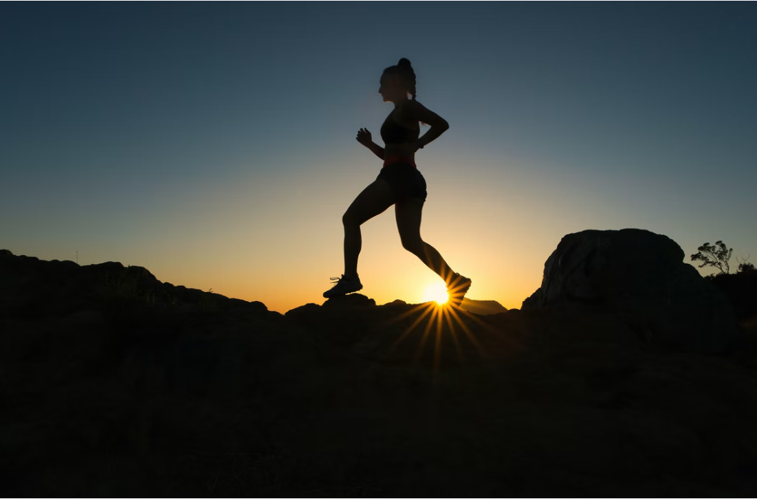 A woman runs up a trail during sunset