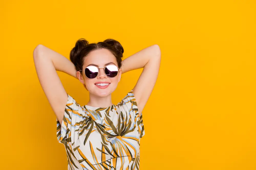 Photo of shiny dreamy lady dressed print t-shirt dark glasses arms behind head empty space isolated yellow color background